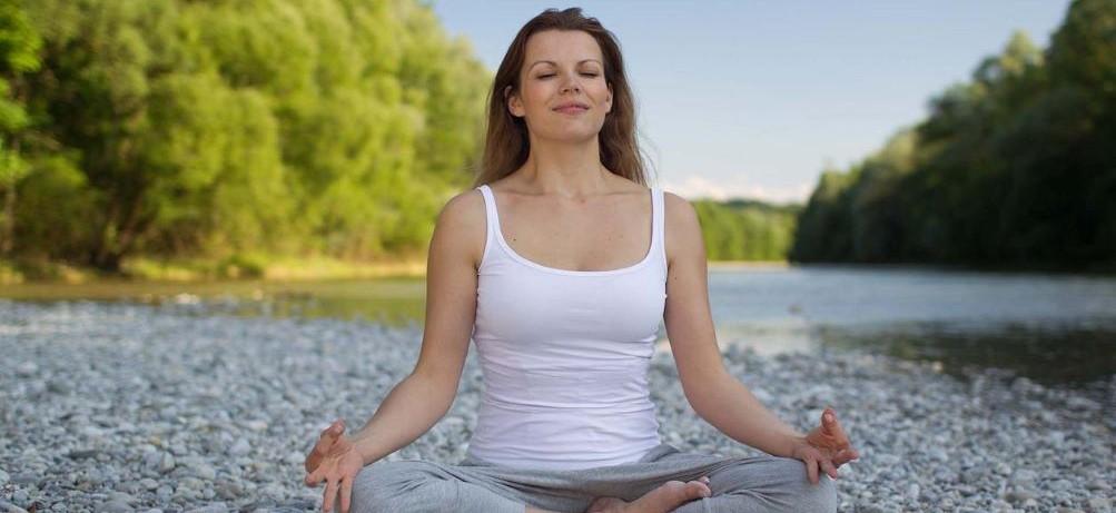 image of a woman meditating in nature to illustrate page about stress management